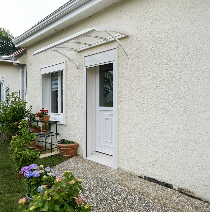 Entrée de maison individuelle avec porte d'entrée blanche vitrée et fenêtre assortie, protégées par marquise en aluminium blanc
