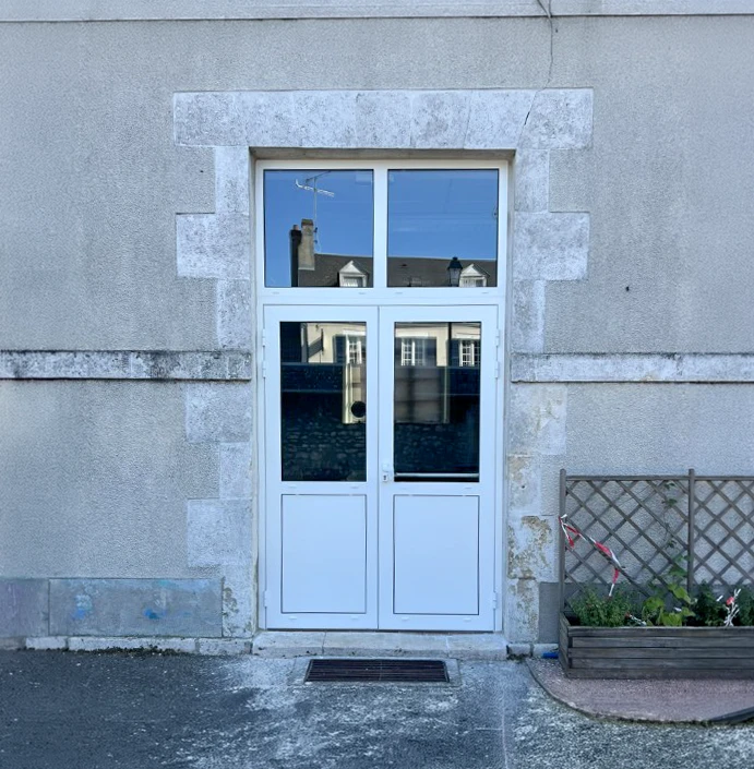 Un homme en t-shirt rouge travaille dans un atelier de menuiserie extérieur couvert