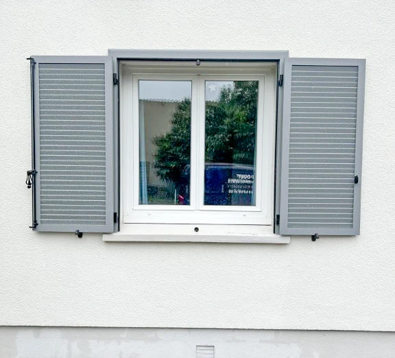 Couple dans magasin de matériaux regardant échantillons de revêtements de sol, homme en chemise à carreaux jaune tenant catalogues, femme souriante l'accompagnant