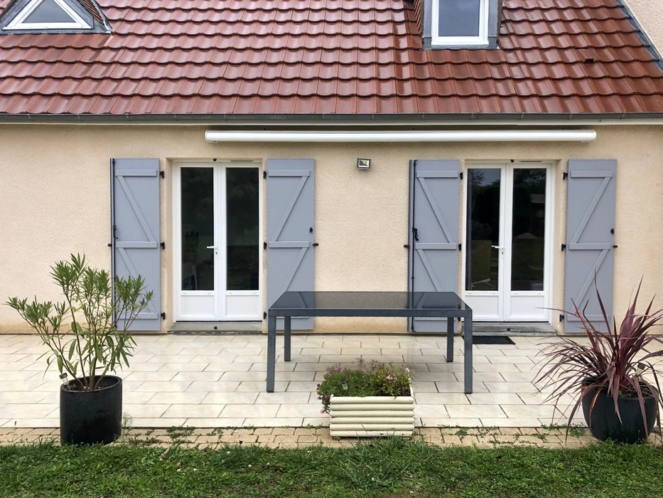 Entrée principale d'une maison avec porte rouge en PVC ou composite, dotée d'un vitrage décoratif à arc surbaissé et panneau inférieur mouluré