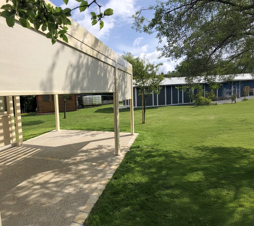 pergola moderne dans une maison contemporaine entourée d'un jardin et d'une piscine